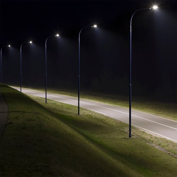 Reihe von Straßenlaternen entlang einer Straße bei Nacht