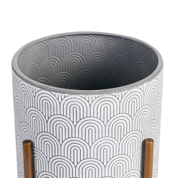 Zylindrischer Übertopf aus Metall mit geometrischem Bogenmuster auf einem Metallgestell.