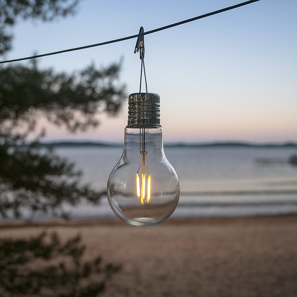 Hängende Glühbirne im Freien mit Gewässer im Hintergrund