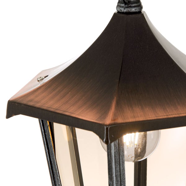 Nahaufnahme einer Außenleuchte im Laternen-Design mit kupferfarbenem Metalldach und sichtbarem Leuchtmittel.