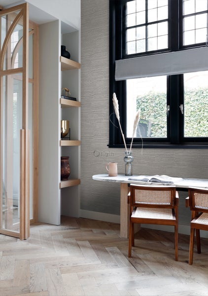 Heller Raum mit Bücherregal, Tisch und Stühlen vor gemusterter Tapete