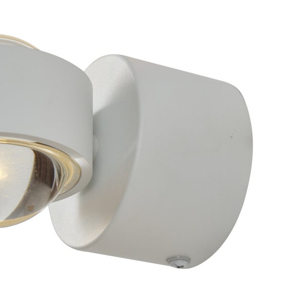 Moderner Wandstrahler aus Metall in Weiß mit runder Glaslinse.