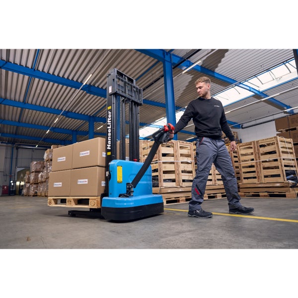 Ein Mann bedient einen blauen elektrischen Deichselstapler in einer Lagerhalle. Auf der Palette liegen Kartons.