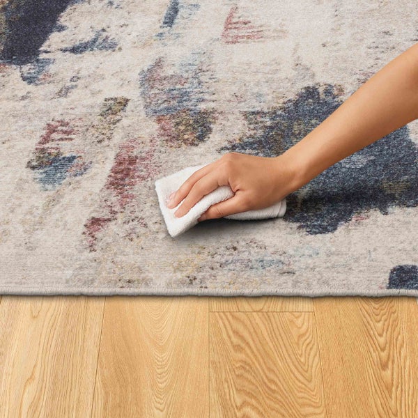 Teppichreinigung mit einem Tuch auf einem Teppich mit abstraktem Muster.