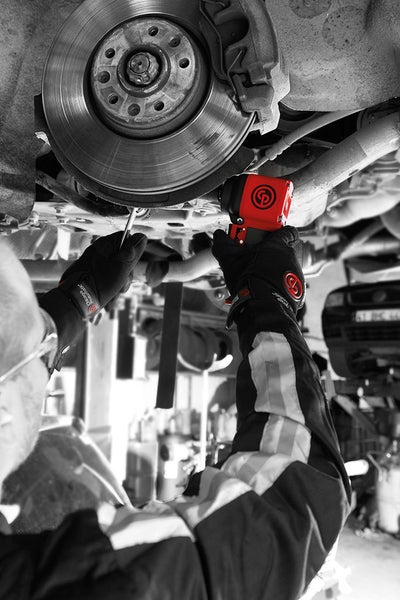 Ein Mechaniker arbeitet mit einem Schlagschrauber an einem Auto.