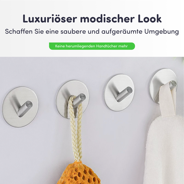 Vier silberfarbene Wandhaken mit Handtuch und Badeschwamm