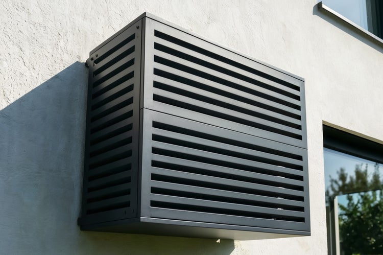 Wärmepumpenverkleidung mit horizontalen Lamellen an Hauswand montiert