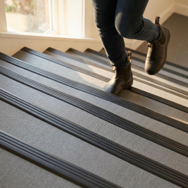 Eine Person geht eine Treppe mit rutschfesten Stufenkantenprofilen hinunter.