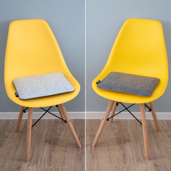Zwei Sitzkissen aus Filz in Hellgrau und Dunkelgrau auf gelben Schalenstühlen mit houten Beinen.
