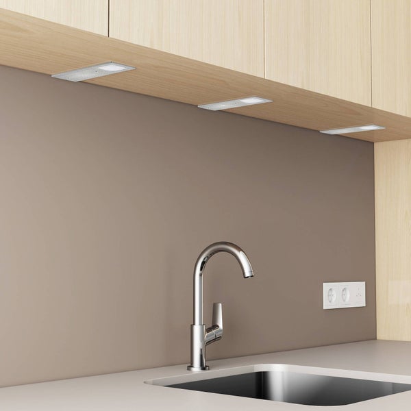 Rechteckige LED-Unterbauleuchten montiert unter Küchenoberschränken aus Holz über einer Spüle mit verchromter Armatur.