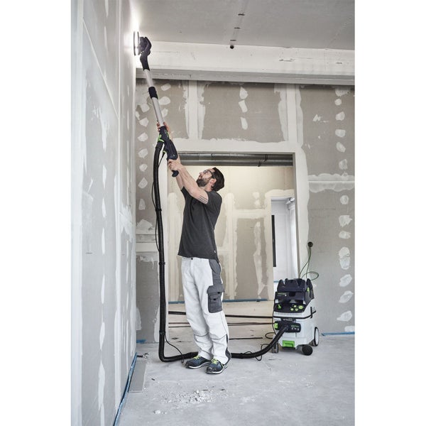 Handwerker nutzt einen Festool Langhalsschleifer mit Absaugmobil zum Schleifen einer Trockenbauwand in einem hellen Raum.
