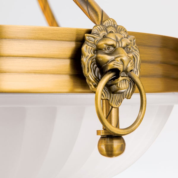 Detailansicht einer Hängeleuchte aus Metall mit Löwenkopf Ornament und Ring in antiker Optik.