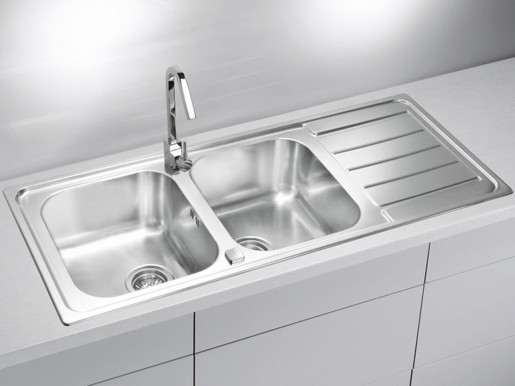 Edelstahl Einbauspüle mit zwei Becken und Abtropffläche sowie Küchenarmatur integriert in eine Küchenarbeitsplatte.