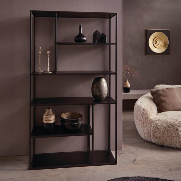 Modernes asymmetrisches Metallregal in Schwarz mit Dekoration in einem gemütlich eingerichteten Wohnzimmer mit flauschigem Sessel.