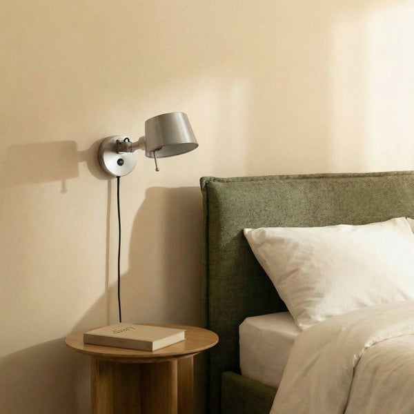 Wandleuchte neben Nachttisch und Bett