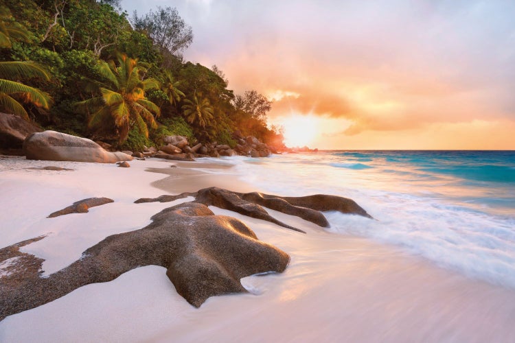Strandlandschaft mit Felsen, Sand und tropischer Vegetation im Sonnenuntergang