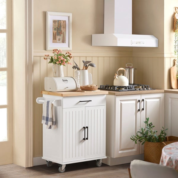 Küchenszene mit einem weißen Küchenwagen mit Holzplatte, einer Dunstabzugshaube und Küchenutensilien.