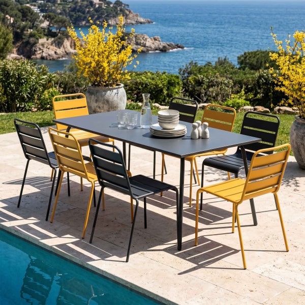 Moderne Garten-Essgruppe auf einer hellen Terrasse mit Meerblick. Rechteckiger Metalltisch mit acht Metallstühlen. Helle, organisierte Atmosphäre.