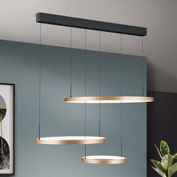 Moderne LED Pendelleuchte mit drei runden Ringen in Metalloptik an einer Deckenhalterung in einem Wohnraum.