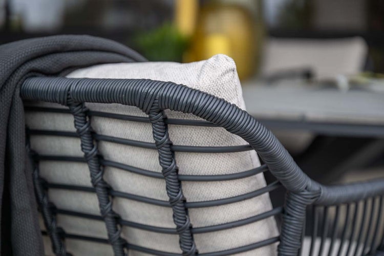 Detailansicht einer Gartenstuhl-Rückenlehne aus grauem Seilgeflecht mit hellem Kissen und grauer Decke.