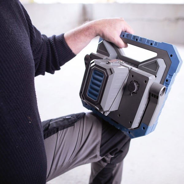 Eine Person hält eine tragbare Baustellenleuchte.