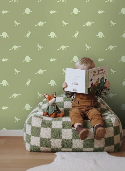 Szene mit Kind, das auf einem Schachbrettmuster-Sitzsack sitzt und ein Buch vor einer Wand mit Dinosaurier-Motiv liest