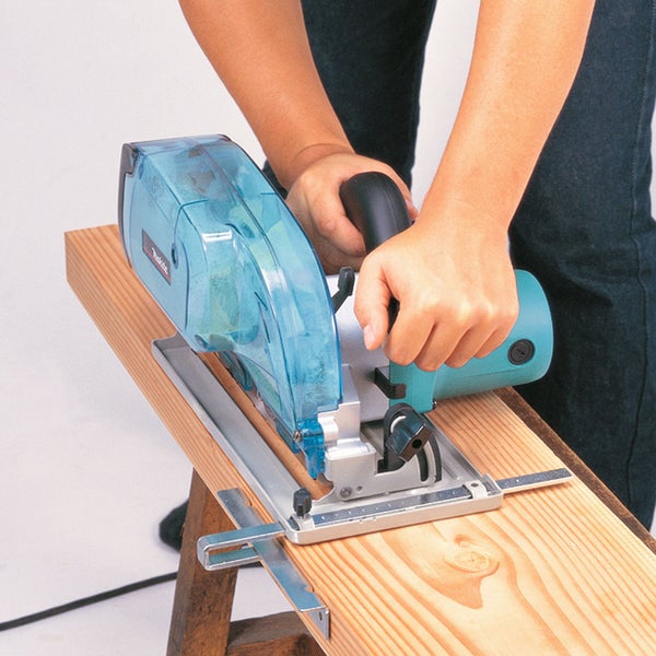 Eine Person schneidet ein Holzbrett mit einer Makita Handkreissäge inklusive Staubbox.