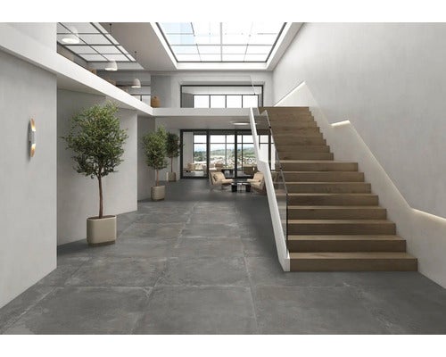 Heller Eingangsbereich mit grauem Fliesenboden, Treppe mit Glasgeländer und Pflanzen