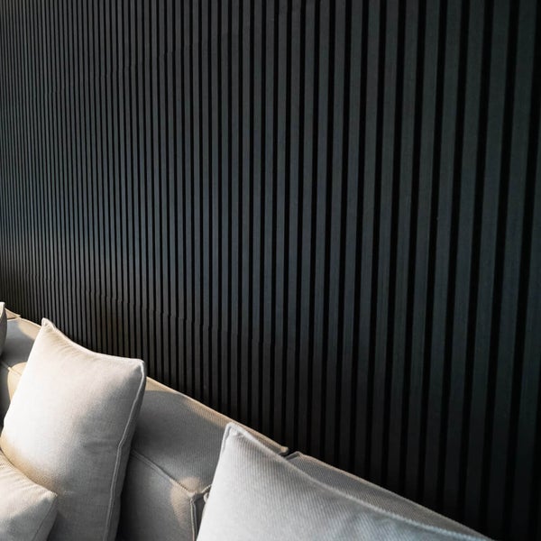 Wandverkleidung aus vertikalen Holzlamellen hinter einem Sofa mit Kissen in einem modernen Wohnraum