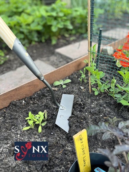 Gartenhacke im Einsatz in einem Hochbeet mit jungen Pflanzen
