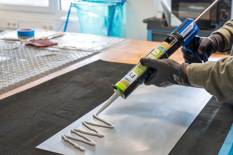 Auftragen von Klebstoff mit einer Kartuschenpistole auf eine Platte