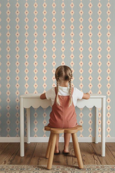 Kindertapete mit Rautenmuster vor einem Schreibtisch mit Kind auf einem Hocker.