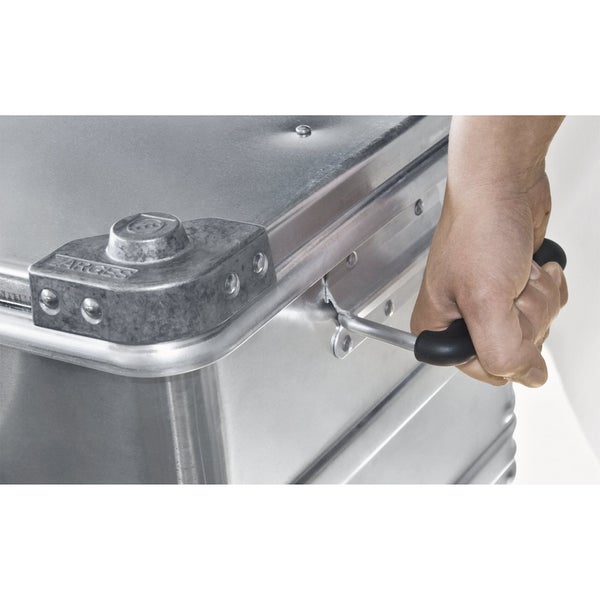Eine Hand greift den Tragegriff einer stabilen Zarges Aluminium Transportbox.