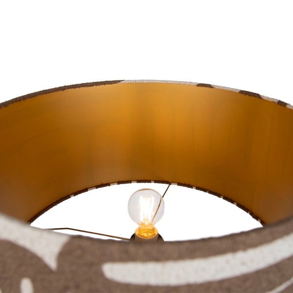 Runder Lampenschirm mit gemustertem Textilbezug und metallischer Innenseite sowie eingesetzter Glühlampe.