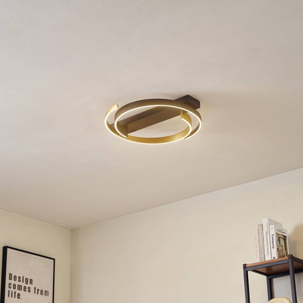 Moderne LED-Deckenleuchte in Ringform, montiert an der Decke eines Zimmers mit Regal und Poster.