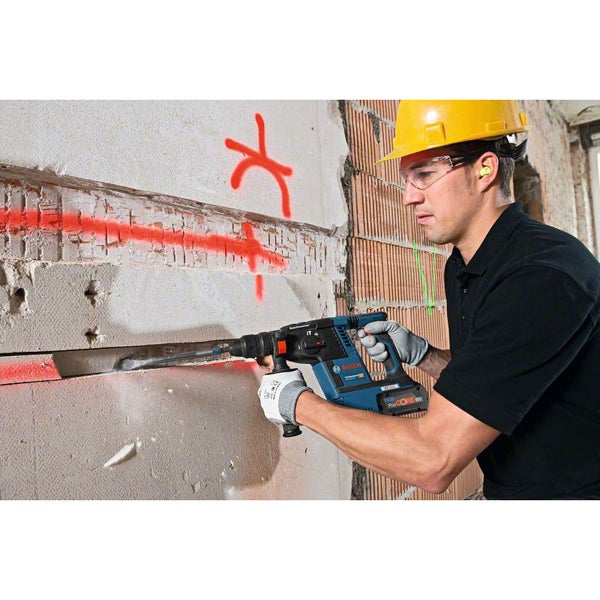 Ein Bauarbeiter verwendet einen Bohrhammer zum Stemmen in eine Wand auf einer Baustelle.