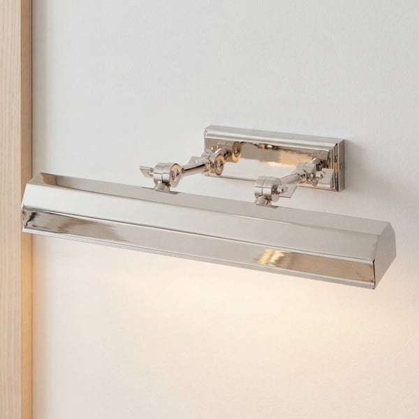Bilderleuchte aus glänzendem Metall mit verstellbarem Gelenkarm, an der Wand montiert und nach unten leuchtend.