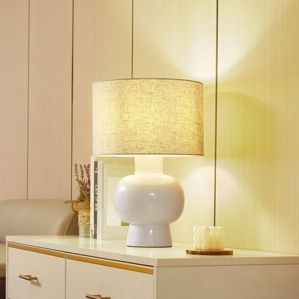 Dekorative Tischleuchte mit Stoffschirm auf einem Nachttisch.