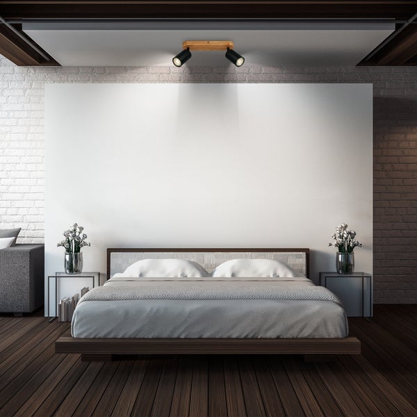 Zweiflammiger Deckenstrahler mit Holzsockel und schwarzen Metallspots in einem modern gestalteten Schlafzimmer über dem Bett.