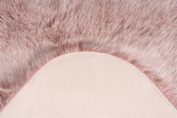 Nahaufnahme eines rosa Kunstfellteppichs mit weichem Hochflor und rutschfester Rückseite.