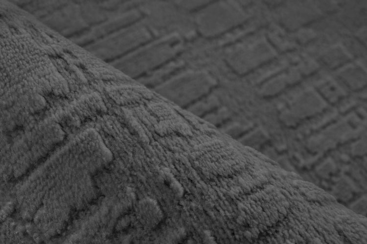 Strukturierter Teppich mit geometrischem Reliefmuster als Nahaufnahme.
