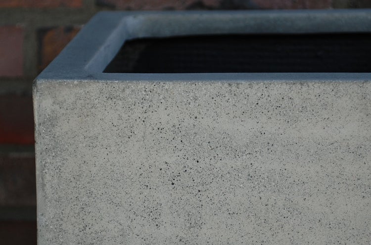 Detailaufnahme eines Pflanzgefäßes aus Beton mit offenporiger Oberflächenstruktur.