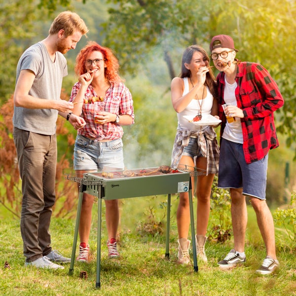 Eine Gruppe von Freunden grillt im Freien auf einem Holzkohlegrill.