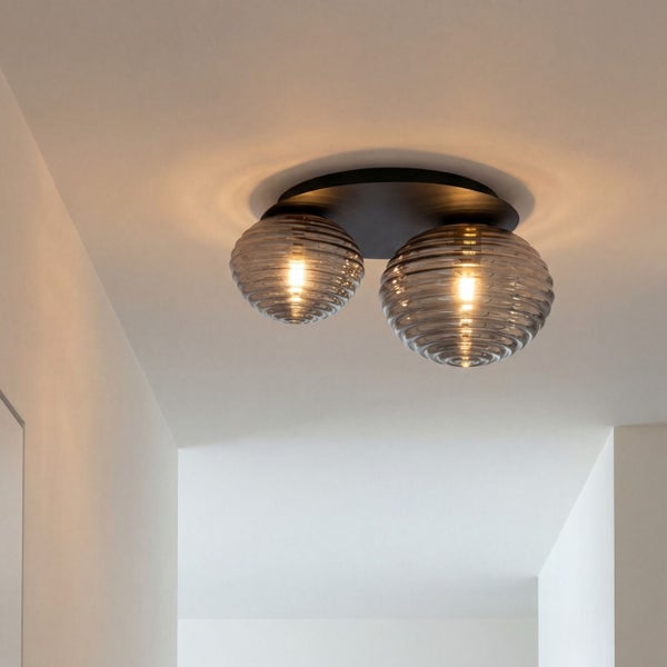 Zweiflammige Deckenleuchte mit geriffelten Schirmen aus Rauchglas und schwarzer Halterung an einer weißen Decke.
