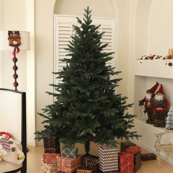 Künstlicher Weihnachtsbaum in einem festlich dekorierten Wohnzimmer mit Weihnachtsgeschenken und Dekofiguren.