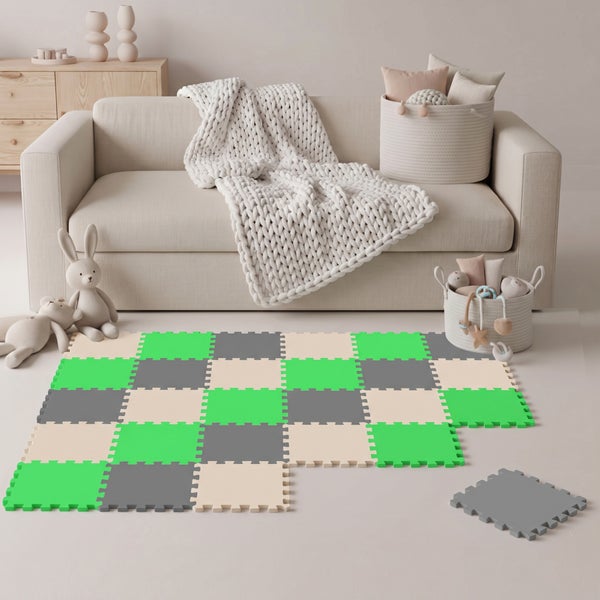 Bunte Schaumstoff Puzzlematte mit ineinandergreifenden Puzzleteilen als Spielunterlage im Wohnzimmer vor einem Sofa.