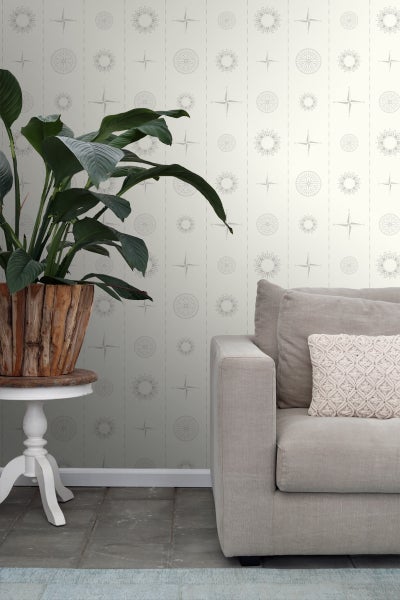 Wohnzimmer mit gemusterter Tapete, Sofa und Pflanze im Holzkübel