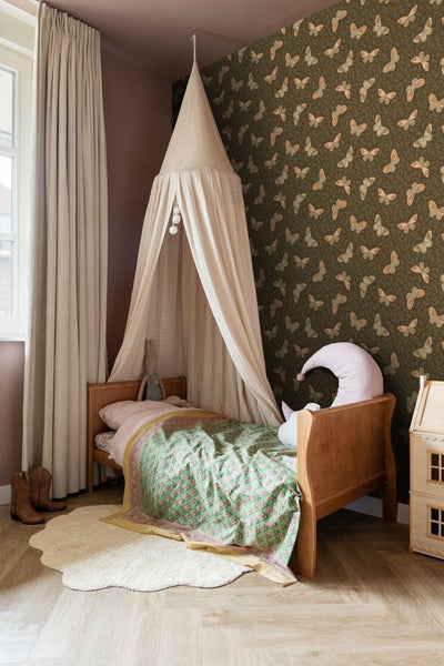 Kinderzimmer mit Bett, Baldachin, Tapete mit Schmetterlingsmuster und dekorativen Elementen für eine gemütliche Atmosphäre.