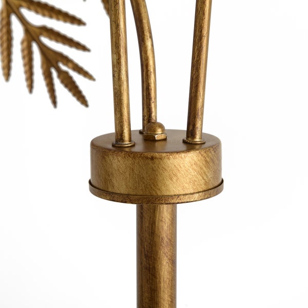 Detail einer goldfarbenen Metalllampe mit Blättermotiv und drei Streben auf einem runden Verbindungselement.