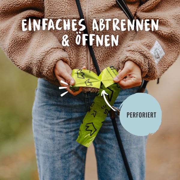 Person reisst einen perforierten Kotbeutel ab